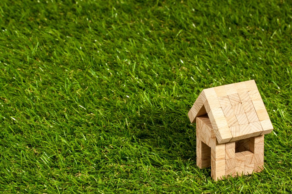 Wooden model house on grass