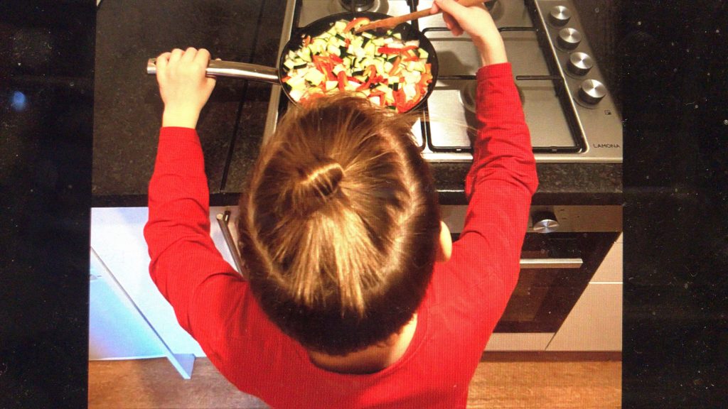 Child stir frying at the stove