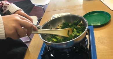 Hands stirring a pan of stir fry vegetables