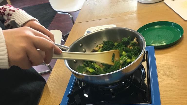 Hands stirring a pan of stir fry vegetables