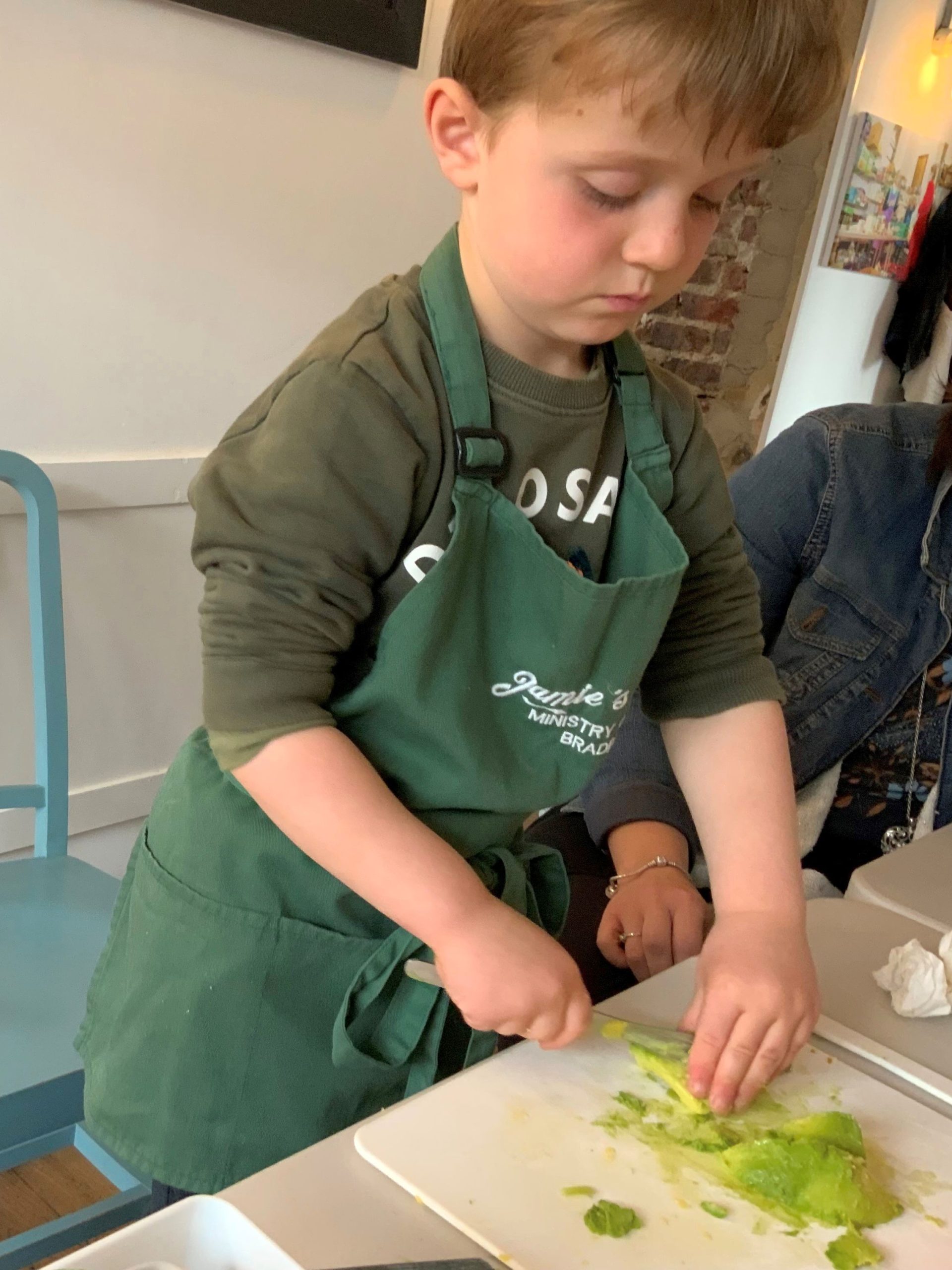 A young boy chopping salad