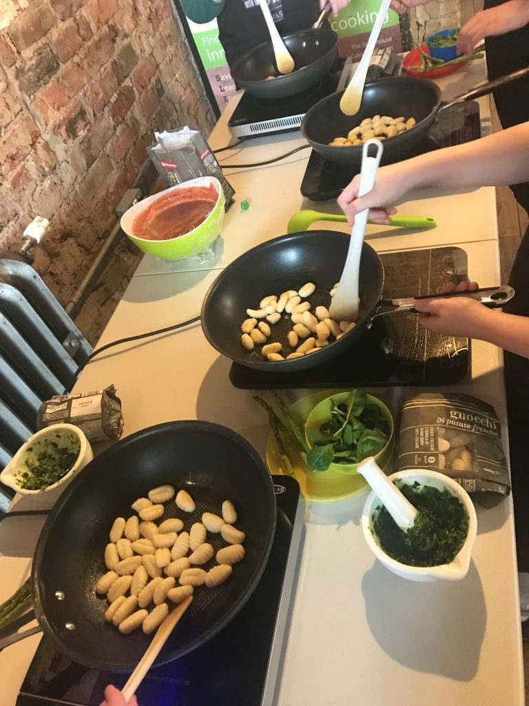 Kids cooking gnocchi in frying pans
