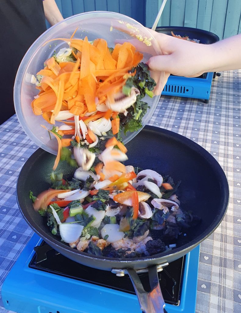 Chopped vegetables being poured into a wok
