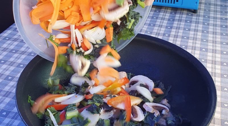 Chopped vegetables being poured into a wok