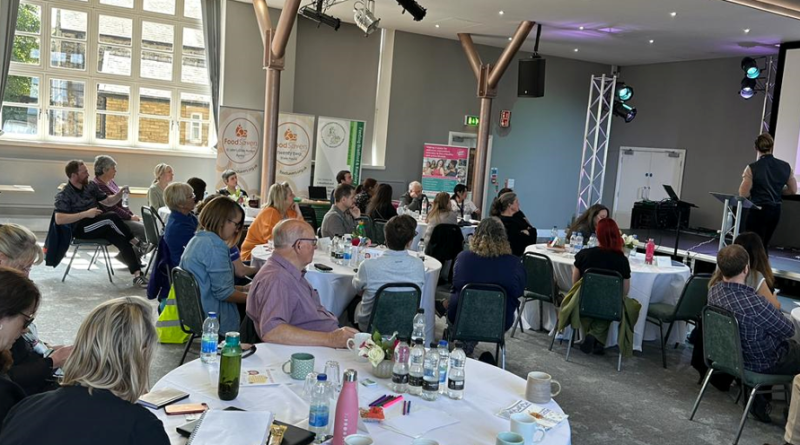 The audience watches from round tables at the Food for Health not Wealth conference