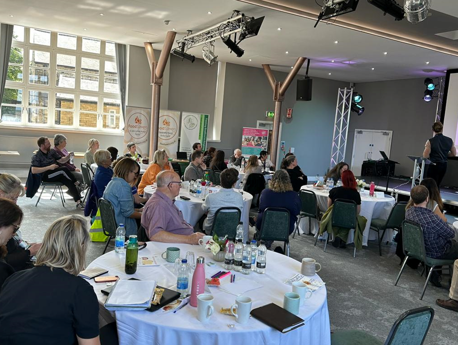 The audience watches from round tables at the Food for Health not Wealth conference