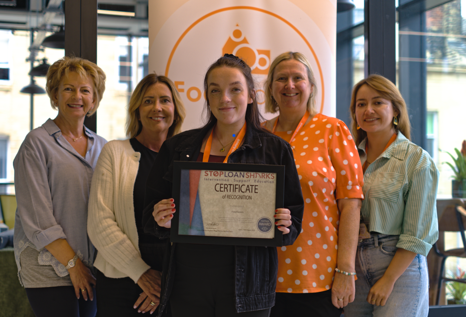 Members of the FoodSavers team hold a certificate recognising official accreditation by Stop Loan Sharks